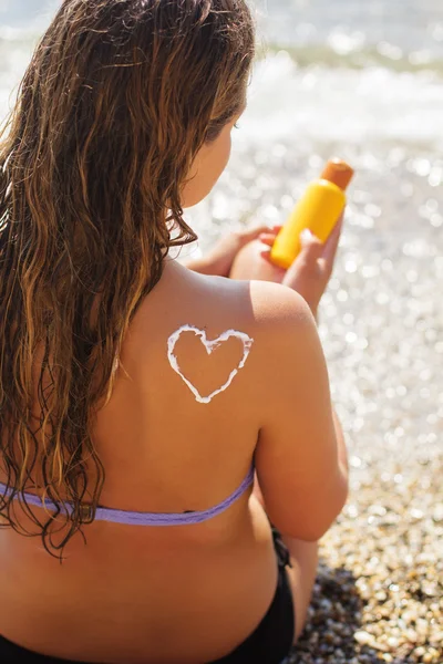 Жінка, що приймає сонячні ванни з сонцезахисним спреєм для засмаги — стокове фото