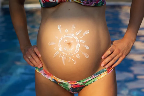 Живот беременной девушки над бассейном — стоковое фото