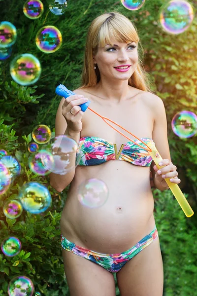 Pregnant girl is making bubbles outdoors — Stock Photo, Image