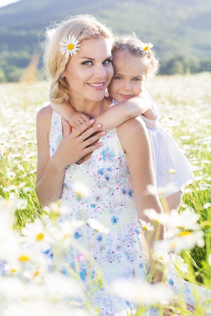 Family mother and daughter in a field of daisy flowers