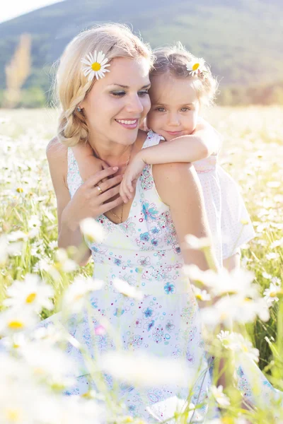 Familjen mor och dotter i ett fält av daisy blommor — Stockfoto