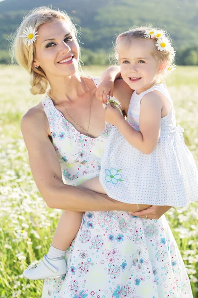 Glad familj mor och dotter i fält av daisy blommor — Stockfoto