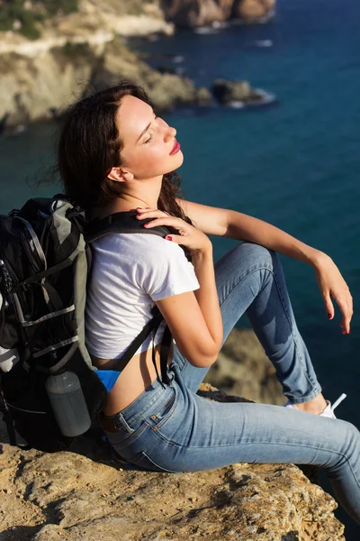 Girl traveler is sitting on rock over sea view — Stock Photo, Image