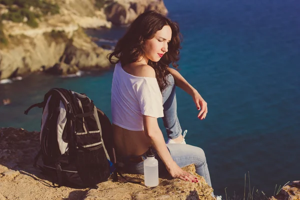 Ragazza zaino in spalla è seduto su roccia sopra vista mare — Foto Stock