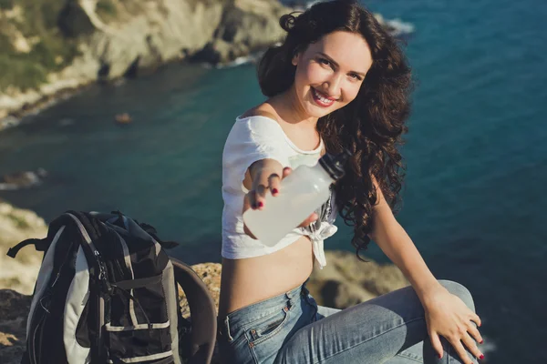 Happy girl backpacker is sitting on rock peak over sea — Stock Fotó