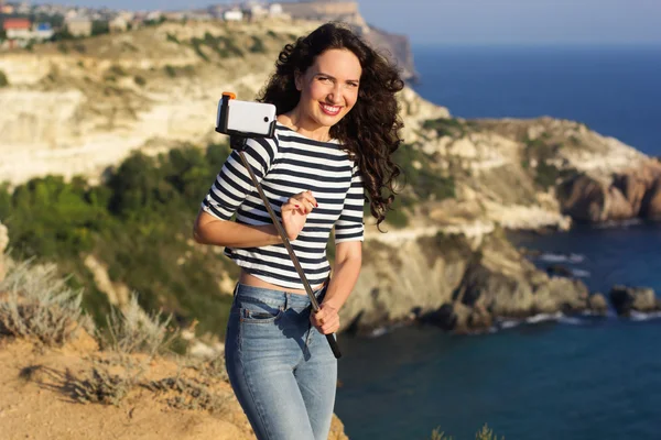 Tourist girl making selfie photo with stick on mountain top — Stockfoto