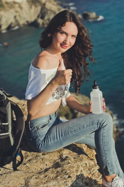 Дівчина рюкзак сидить на скелі над видом на море — стокове фото