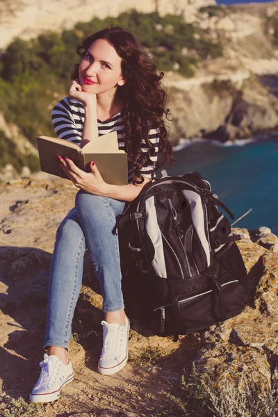 Mulher bonita está lendo livro sobre o pico da rocha — Fotografia de Stock