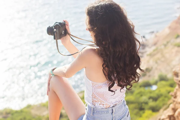 Photographer girl making pictures by old camera on mountain top — Stockfoto