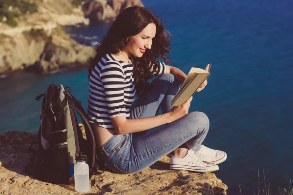 Menina viajante está sentado no pico da montanha e livro de leitura — Fotografia de Stock