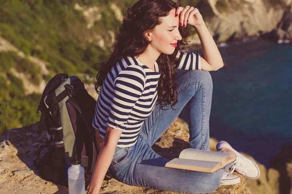 Viajante menina está sentado no livro de rock e leitura — Fotografia de Stock