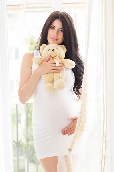 Embarazada feliz mujer está sosteniendo oso de peluche —  Fotos de Stock