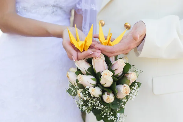 Novia y novios manos está sosteniendo pájaro amarillo origami — Foto de Stock