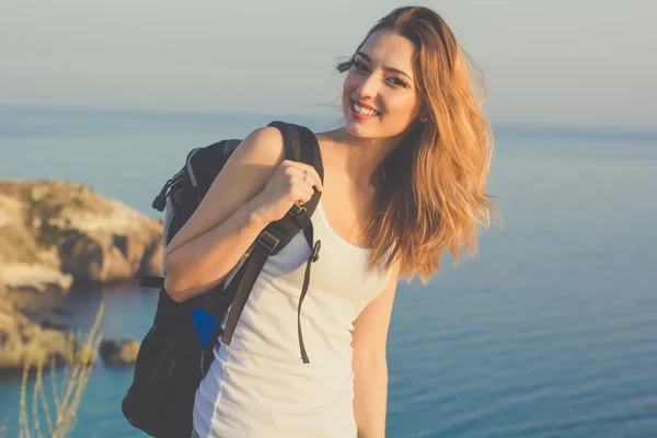 Щаслива дівчина мандрівник стоїть на скелі над видом на море — стокове фото
