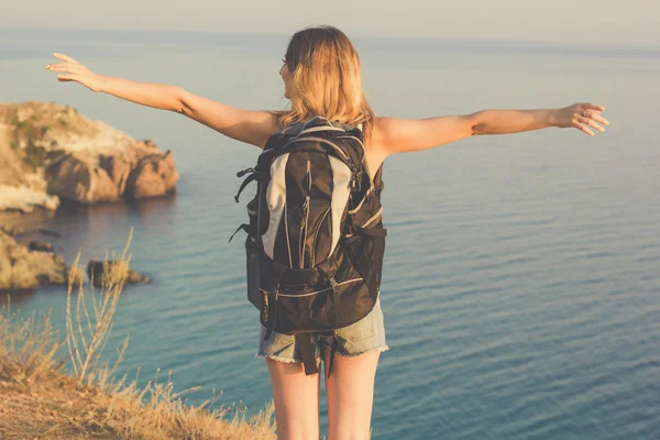 Indietro vista di backpacker giovanissima ragazza è in piedi su roccia — Foto Stock