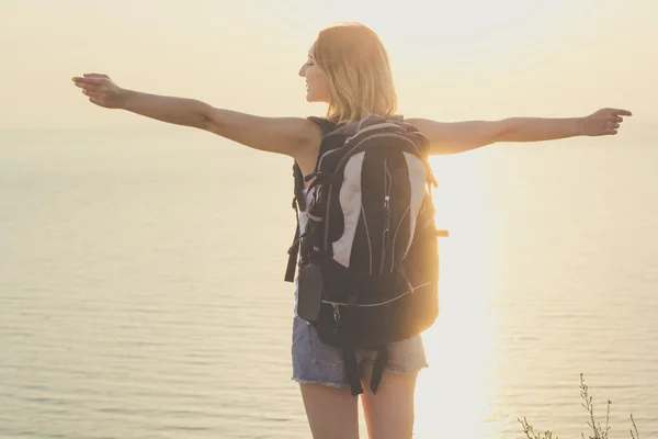 Retrovisore di backpacker ragazza è in piedi su roccia, tramonto — Foto Stock