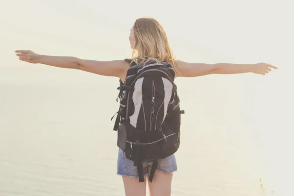 Retrovisore di backpacker ragazza è in piedi su roccia, tramonto — Foto Stock