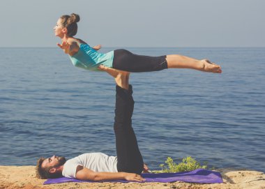 Genç bir çift deniz kıyısında acroyoga egzersizleri pratik vardır 