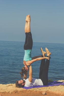 Genç bir çift deniz kıyısında acroyoga egzersizleri pratik vardır 