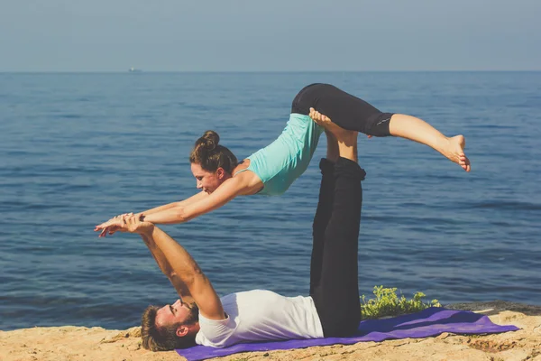 Vackert ungt par män och kvinna gör acro yoga — Stockfoto