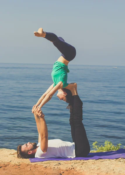 Couple girl and boy are practicing acroyoga on the sea — Stock Photo, Image