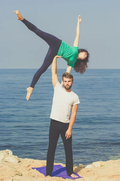 Par flicka och pojke tränar acroyoga på havet — Stockfoto