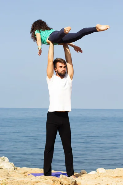 Sportive couple are practicing acroyoga on the beach — Stock Photo, Image