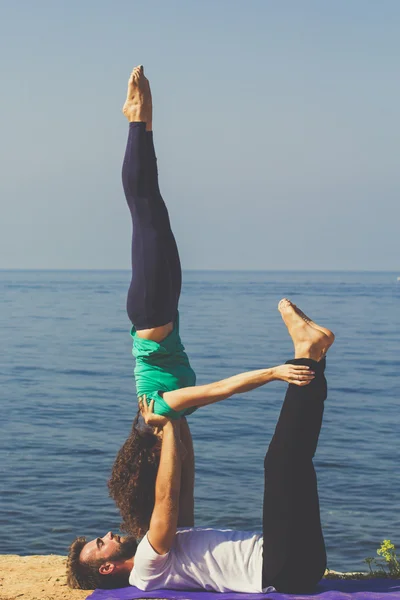 Sportig par tränar yoga på stranden — Stockfoto