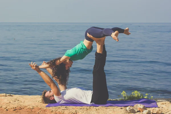 Sportive couple are practicing yoga on the beach — Stock Photo, Image