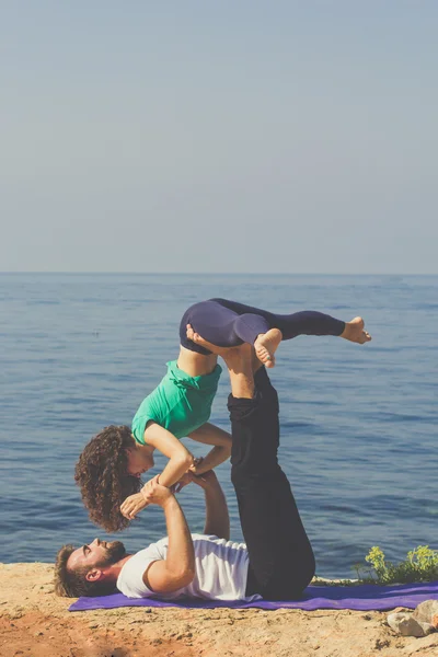 Sportig par tränar yoga på stranden — Stockfoto