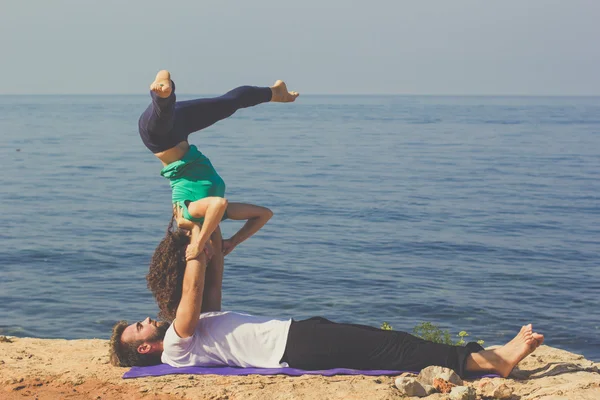 Sportig par tränar yoga på stranden — Stockfoto