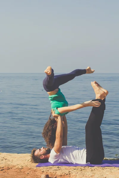 Sportif genç çift sahilde yoga uygulamak — Stok fotoğraf