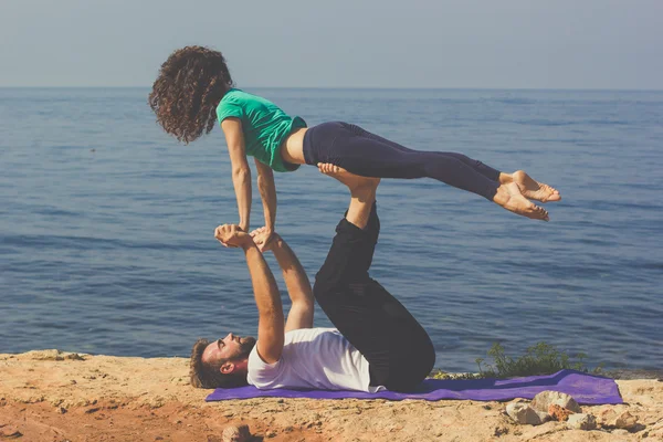 Sportig unga paret gör yoga på stranden — Stockfoto
