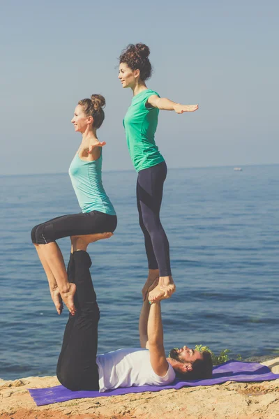 Sportig grupp av tre personer gör acroyoga — Stockfoto