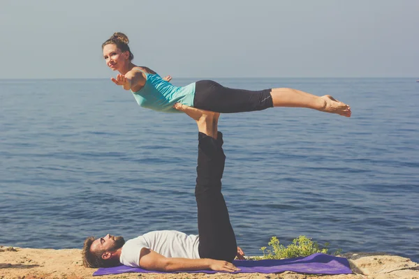 Bella giovane coppia che fa acro yoga sulla spiaggia — Foto Stock