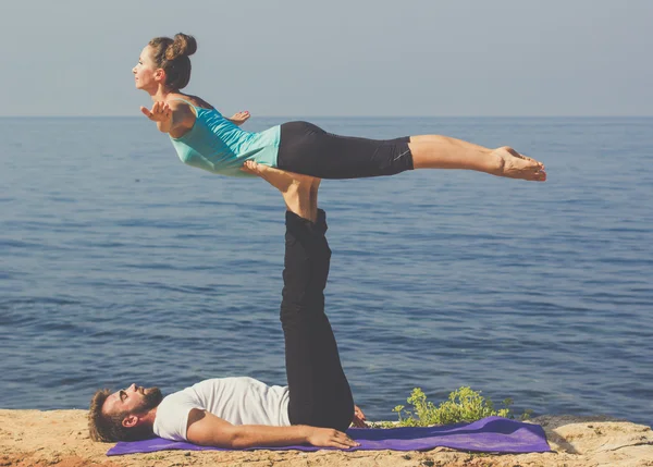 Young couple are practicing acroyoga exercises on the sea coast — Stock Photo, Image