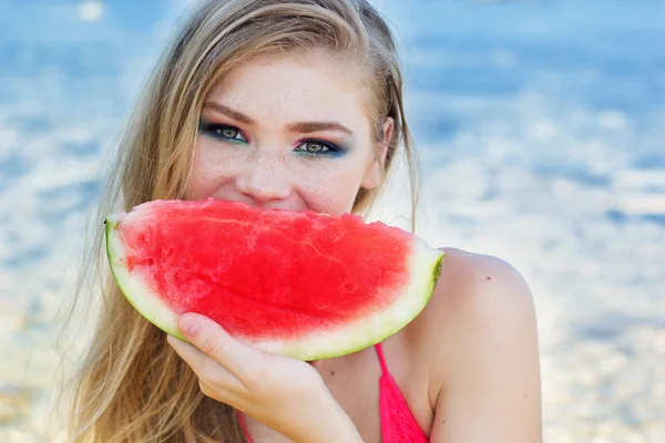 Menina bonita está comendo melancia na praia — Fotografia de Stock