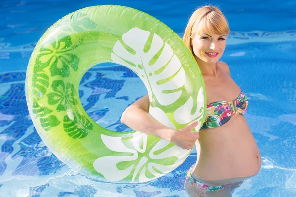 Pregnant woman with green rubber ring in swimming pool — 스톡 사진