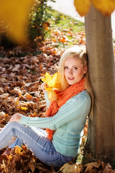 Pretty blonde girl is sitting in autumn park — Stock Photo, Image