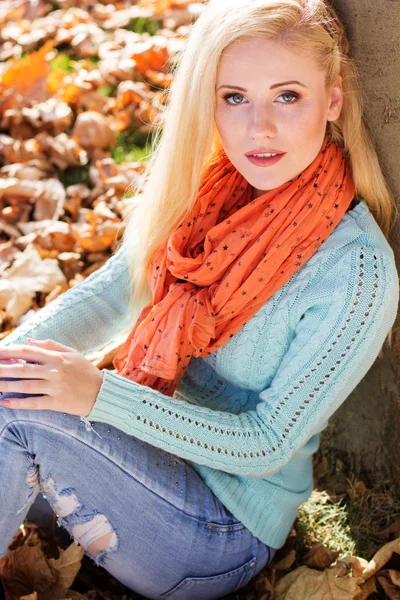 Teenager girl is sitting in park on yellow maple leaves — Stock Photo, Image