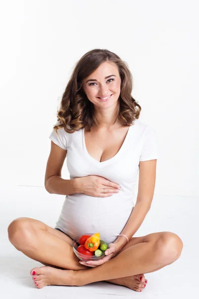 Mulher grávida está segurando prato com legumes — Fotografia de Stock