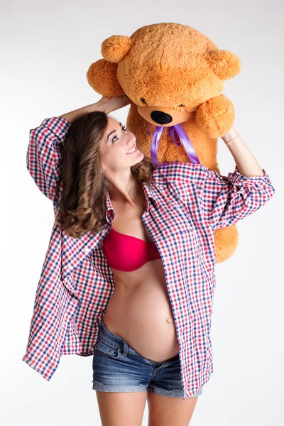 Menina grávida muito feliz está segurando grande urso de brinquedo — Fotografia de Stock