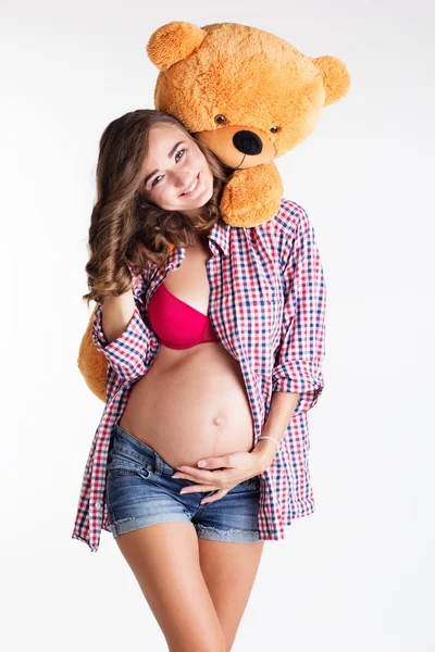 Hermosa chica embarazada está sosteniendo oso de juguete grande — Foto de Stock