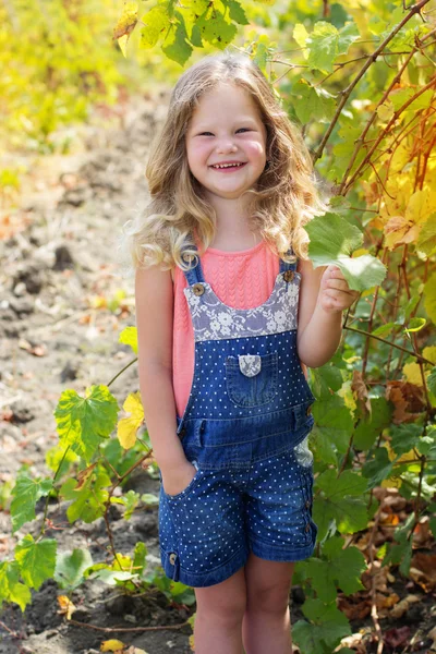 Usmívající se dítě blondýnka v hroznů vinice — Stock fotografie