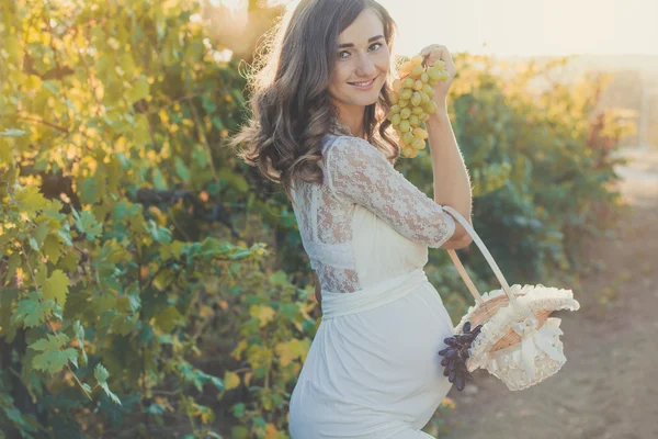 Pregnant girl with bunch of grapes in vineyard — Stock Photo, Image