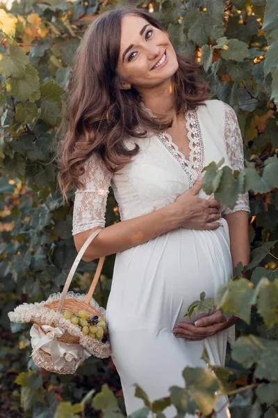 Zwangere vrouw met mandje met druiven buitenshuis — Stockfoto