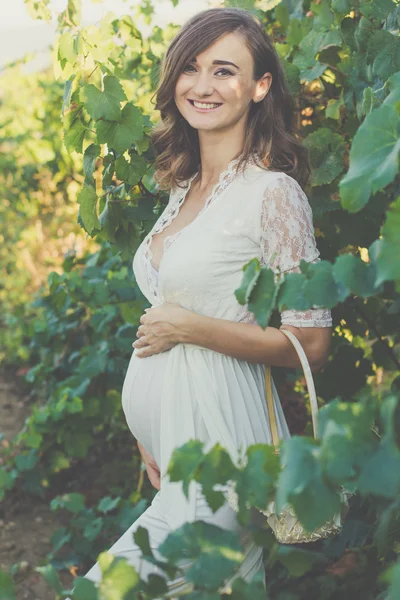 Happy pregnant woman with basket of grapes — Stock Photo, Image