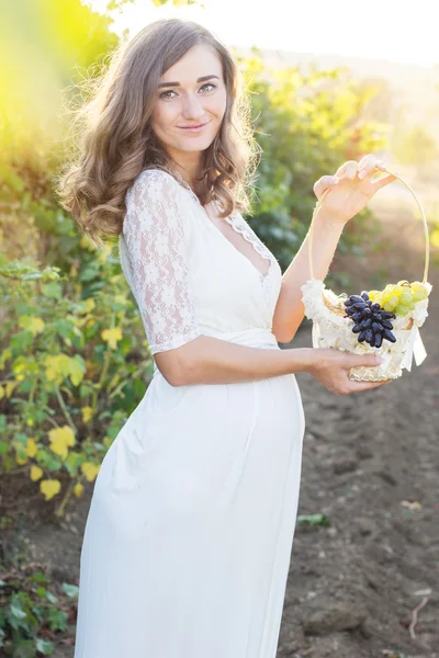 Gelukkig zwangere meisje met mand van druiven — Stockfoto
