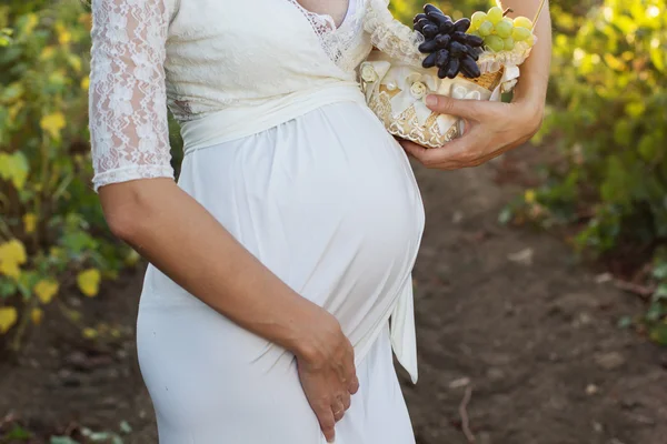 Belly of pregnant woman  with grapes basket — Stock Photo, Image