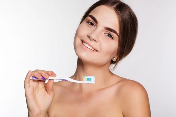 Sonriente chica está sosteniendo cepillo con pasta de dientes aislado en blanco — Foto de Stock